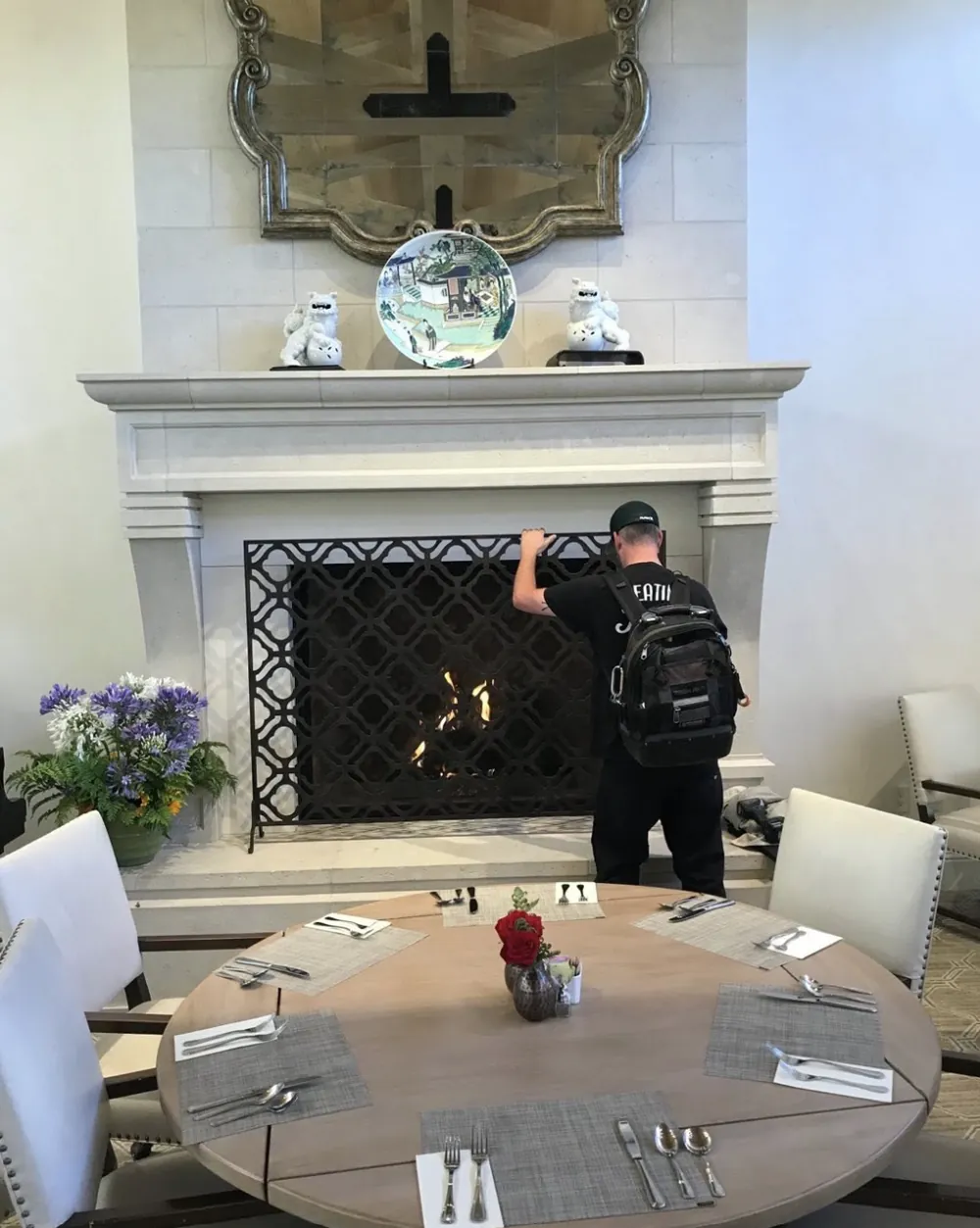 Jeremy at a carved limestone fireplace with a decorative iron screen in a dining room, fire lit