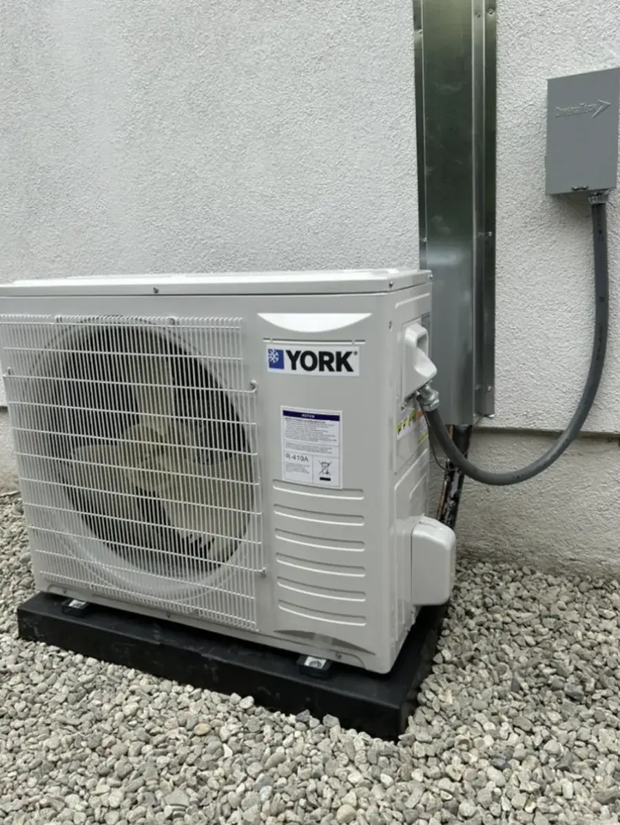 A York outdoor unit mounted on a pad against a stucco wall with its line set covered