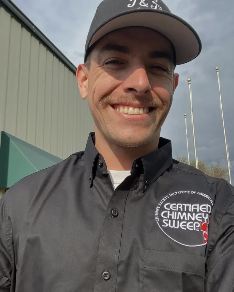 Jeremy Varela, owner of J & J's, smiling in a J and J cap and a CSIA Certified Chimney Sweep shirt